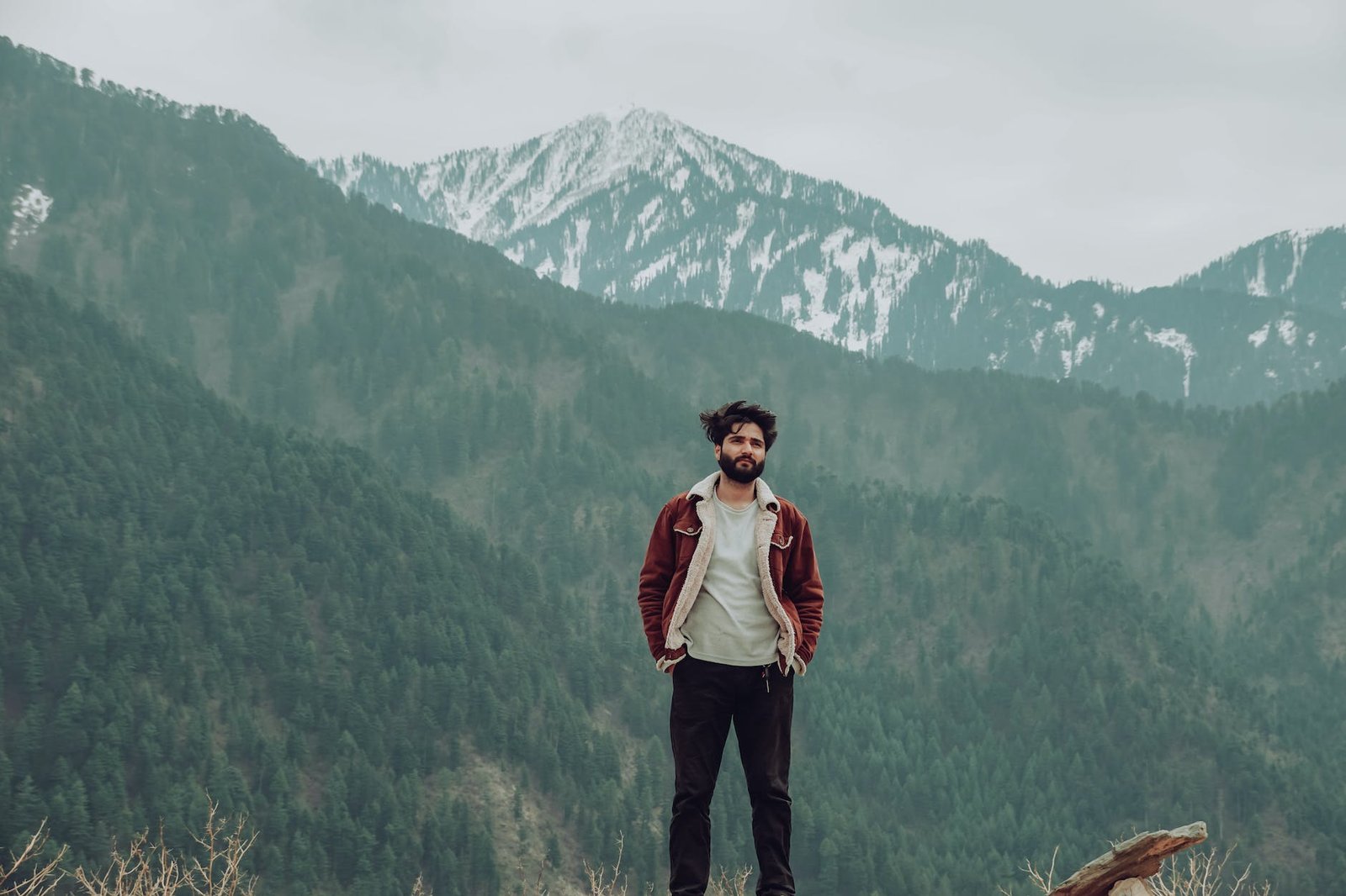 man wearing a jacket standing near the mountains